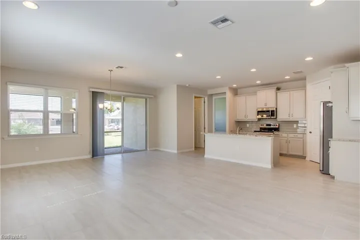 Kitchen with open floor plan, recessed lighting, appliances with stainless steel finishes, a chandelier, and a center island with sink