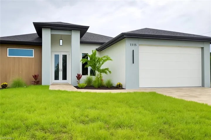 Rear view of house with french doors, a yard, an attached garage, driveway, and a shingled roof