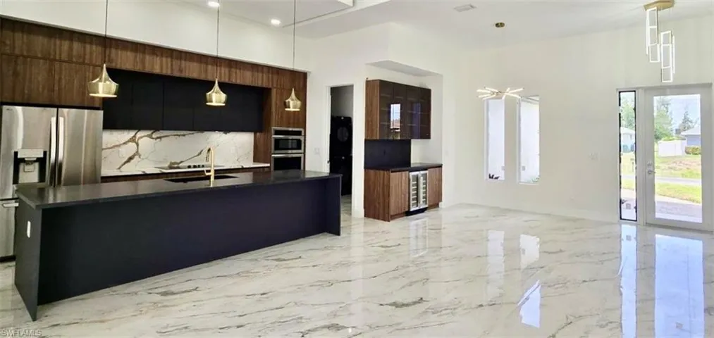 Kitchen with stainless steel appliances, wine cooler, modern cabinets, dark countertops, and a sink