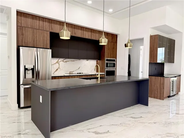 Kitchen with appliances with stainless steel finishes, modern cabinets, light marble finish floors, tasteful backsplash, and wine cooler