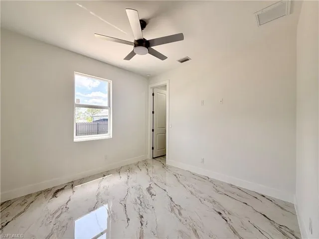 Empty room with light marble finish flooring, baseboards, and ceiling fan