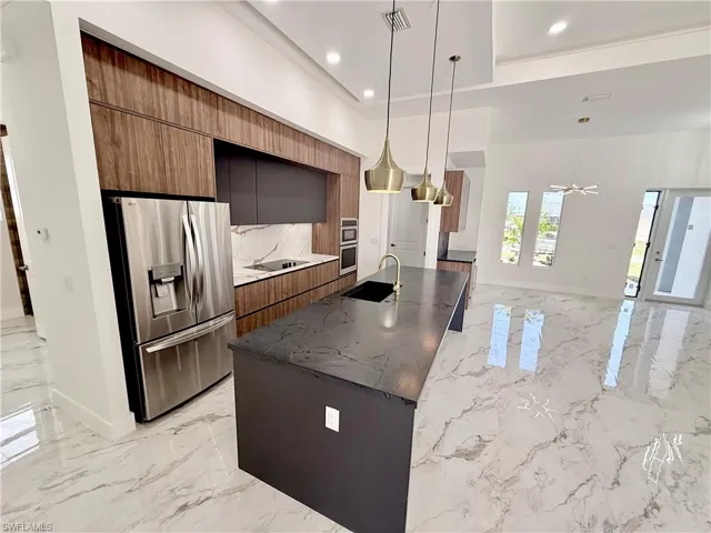 Kitchen with stainless steel appliances, modern cabinets, light marble finish flooring, brown cabinets, and recessed lighting