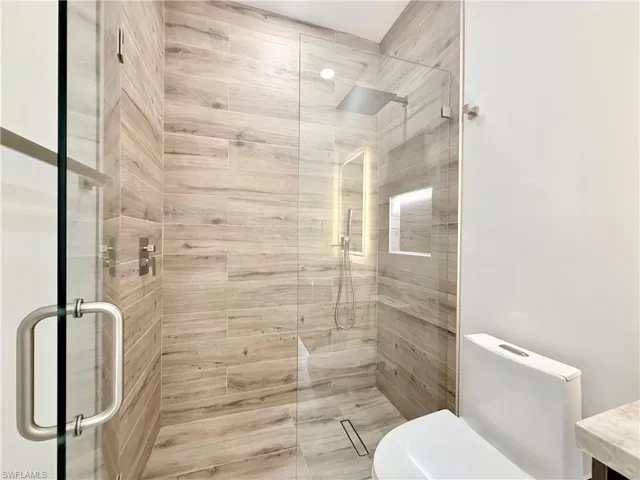 Full bathroom featuring toilet, a stall shower, and vanity