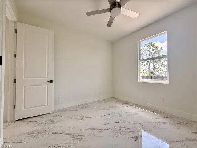 Unfurnished room featuring marble finish floors, baseboards, and a ceiling fan
