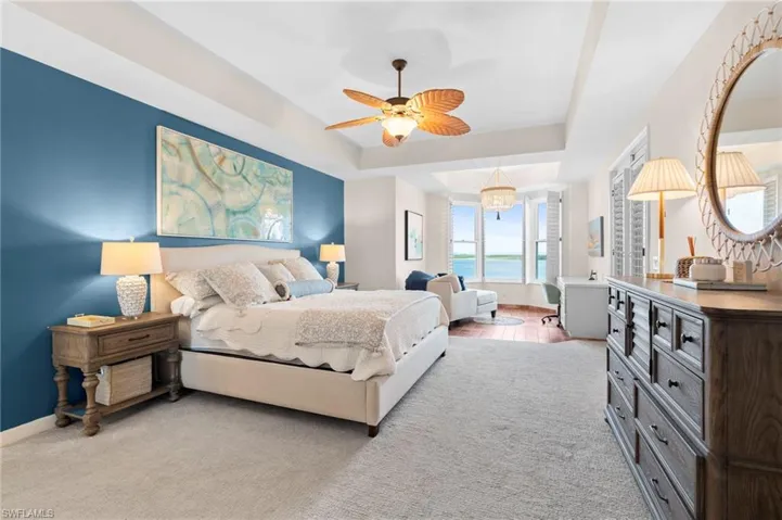 Carpeted bedroom featuring ceiling fan and a raised ceiling