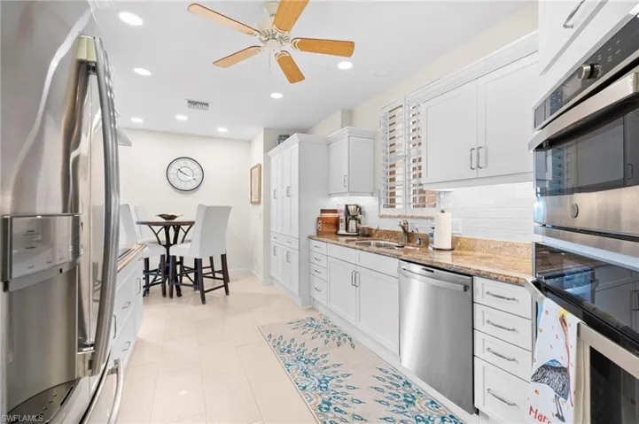 Kitchen featuring appliances with stainless steel finishes, tasteful backsplash, sink, ceiling fan, and white cabinets