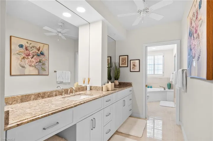 Bathroom with a tub to relax in, vanity, ceiling fan, and tile patterned flooring