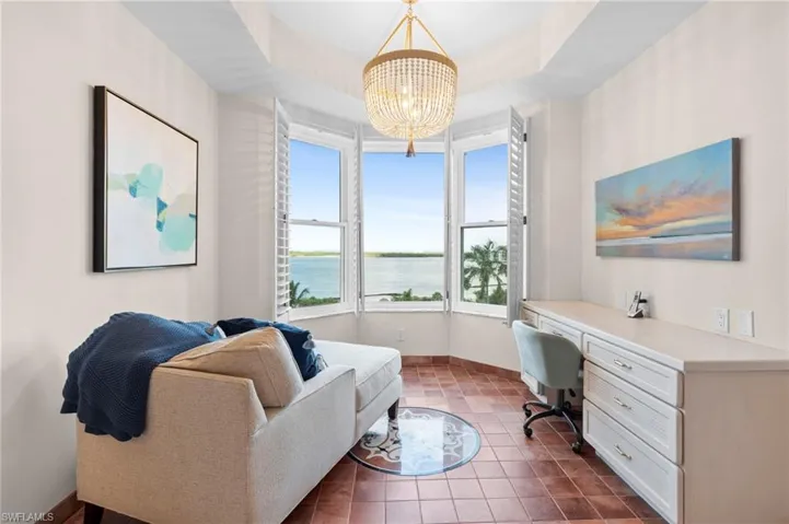 Tiled office with a raised ceiling, an inviting chandelier, and a water view