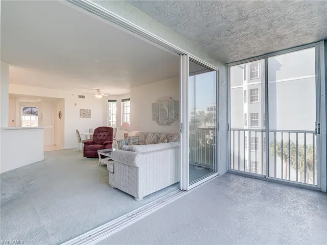 Living room featuring light carpet, a wall of windows, and ceiling fan