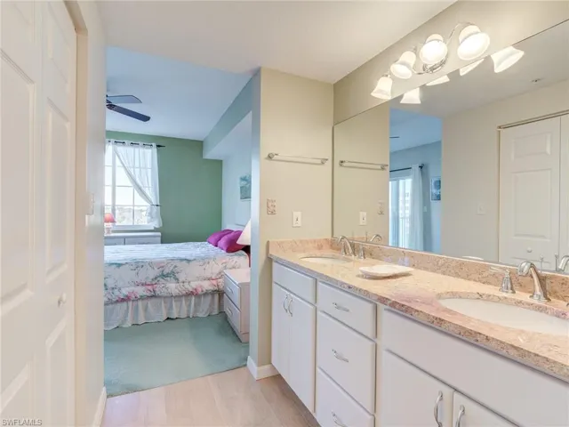 Ensuite bathroom with double vanity, healthy amount of natural light, light wood-style floors, and a ceiling fan