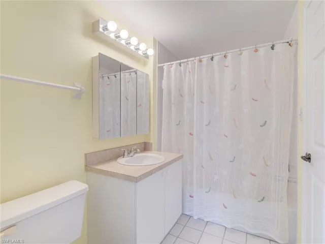 Bathroom with light tile patterned floors, vanity, and shower / bathtub combination with curtain