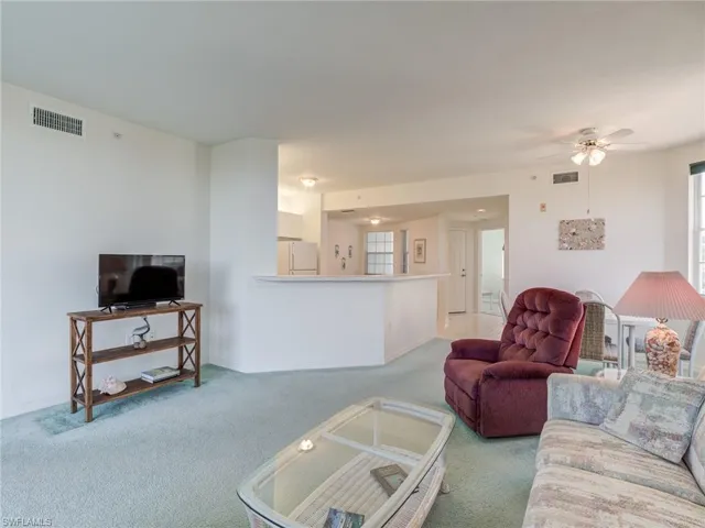 Carpeted living room featuring a ceiling fan and baseboards