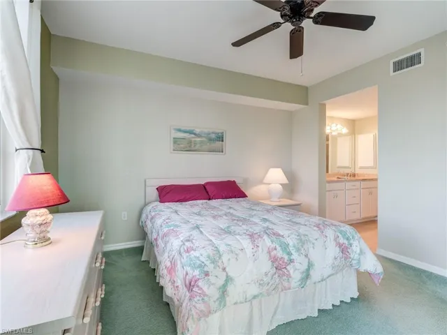 Bedroom with carpet floors, ceiling fan, and ensuite bathroom