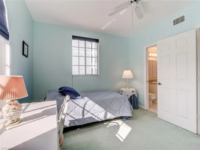 Carpeted bedroom featuring ceiling fan and ensuite bathroom
