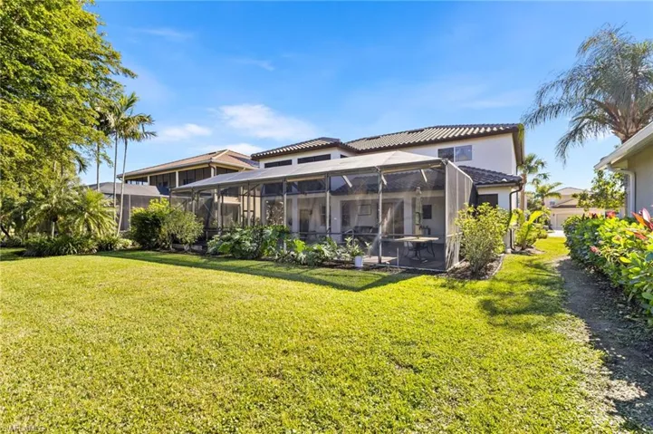 Rear view of house with a lanai and a lawn
