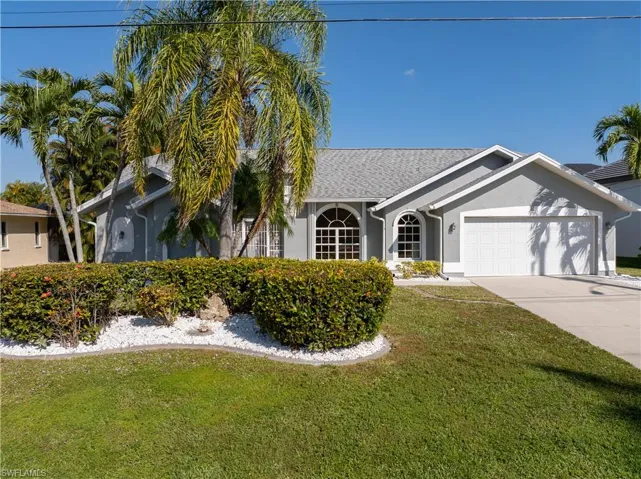 Single story home featuring a front yard, stucco siding, an attached garage, and driveway
