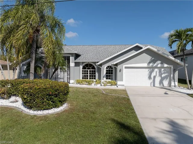 Ranch-style house with a front yard, a shingled roof, stucco siding, drivewa and 2 car garage