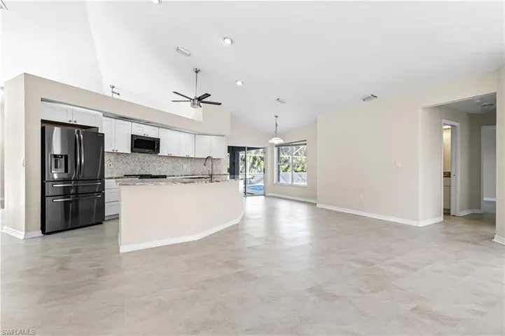 Kitchen with stainless steel refrigerator with ice dispenser, white cabinetry, tasteful backsplash, pendant lighting, and ceiling fan
