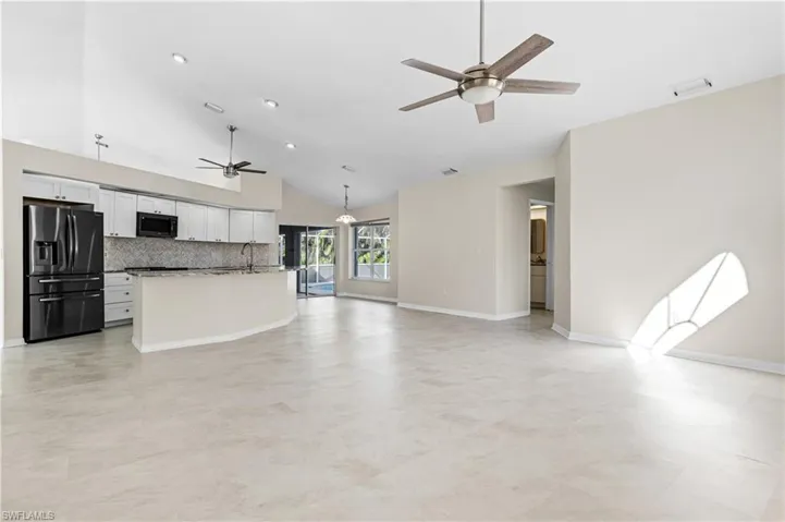 Large living room featuring a ceiling fan, recessed lighting, pool access and high vaulted ceiling