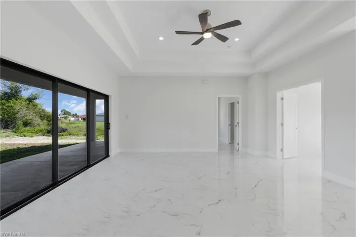 Unfurnished room with tile patterned floors, ceiling fan, and a tray ceiling