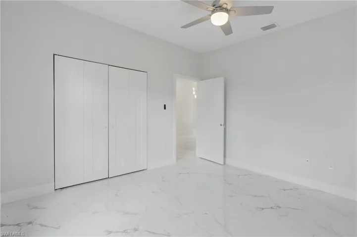 Unfurnished bedroom with light tile patterned flooring, ceiling fan, and a closet