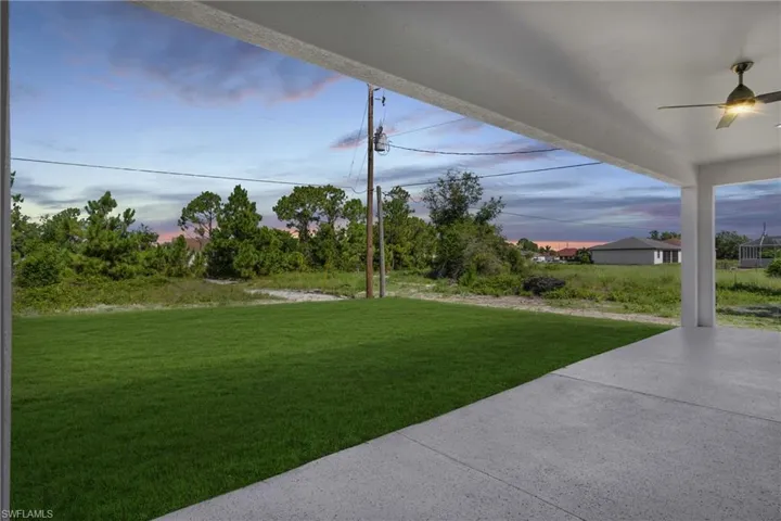 Yard at dusk with ceiling fan and a patio area