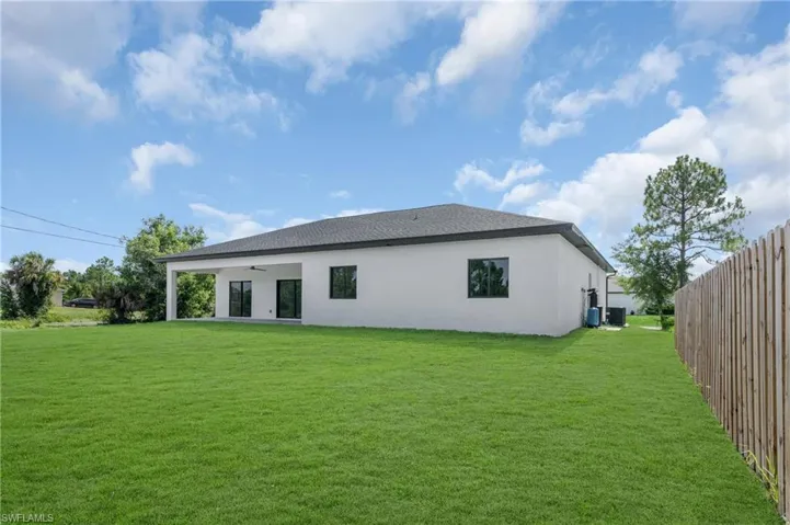 Back of property featuring a patio area, a lawn, and ceiling fan