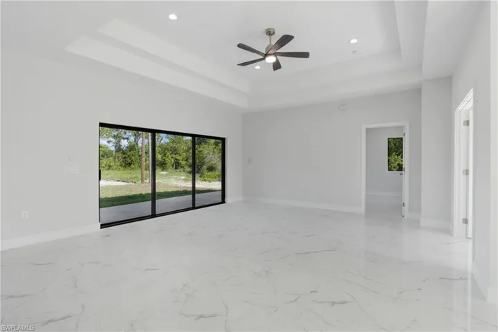 Tiled spare room featuring ceiling fan and a tray ceiling