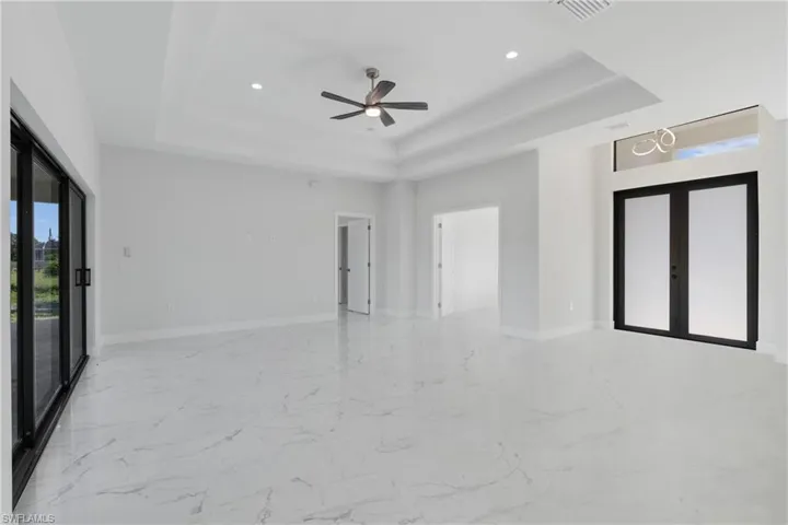 Spare room with french doors, tile patterned floors, ceiling fan, and a raised ceiling