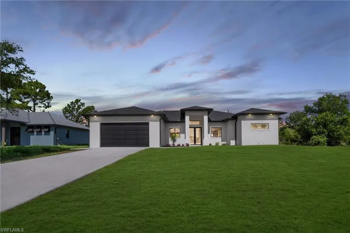 View of front facade featuring a garage and a lawn