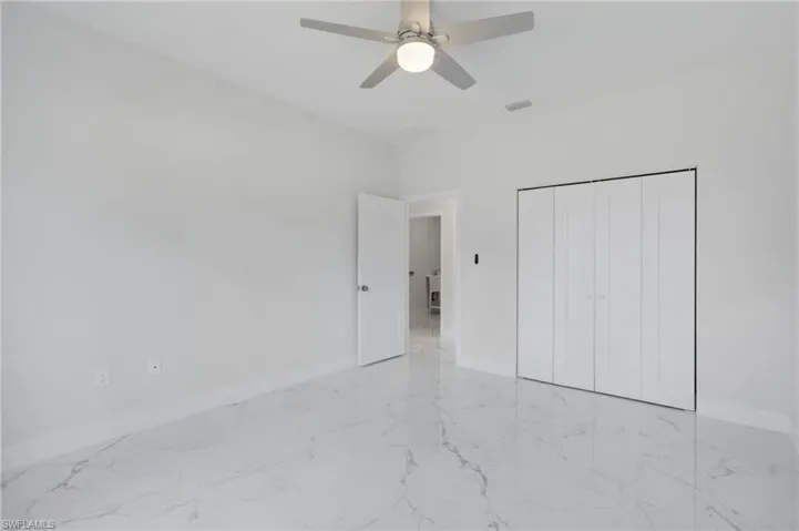 Unfurnished bedroom featuring a closet, light tile patterned floors, and ceiling fan