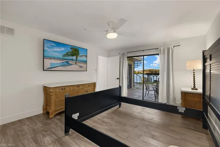 Bedroom with hardwood / wood-style floors, access to outside, and ceiling fan