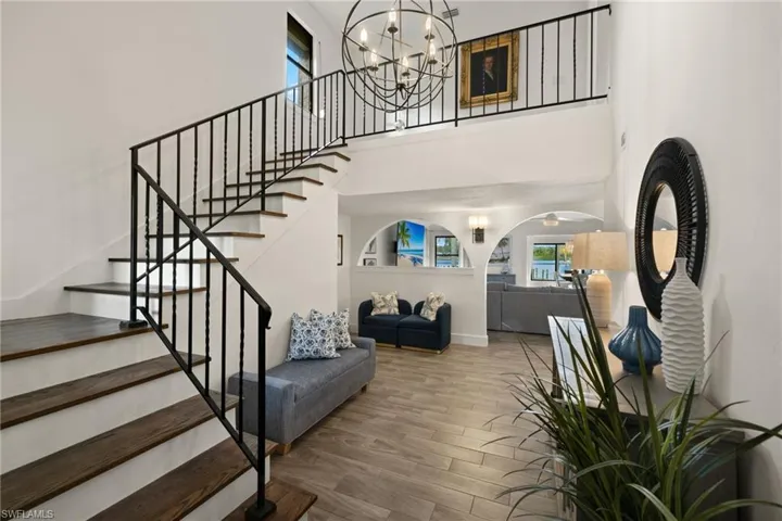 Staircase with an inviting chandelier, wood-type flooring, and a high ceiling