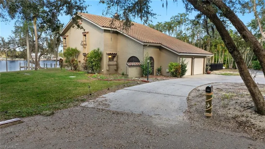 View of front of home with a garage, a front lawn, and a water view
