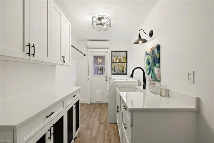 Washroom featuring washer and clothes dryer, light hardwood / wood-style floors, and cabinets