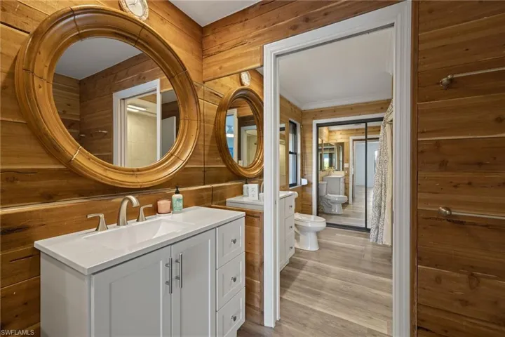 Bathroom featuring wood walls, hardwood / wood-style flooring, vanity, toilet, and a bidet