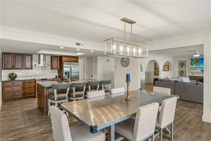 Dining space featuring sink, ceiling fan with notable chandelier, ornamental molding, and dark hardwood / wood-style floors