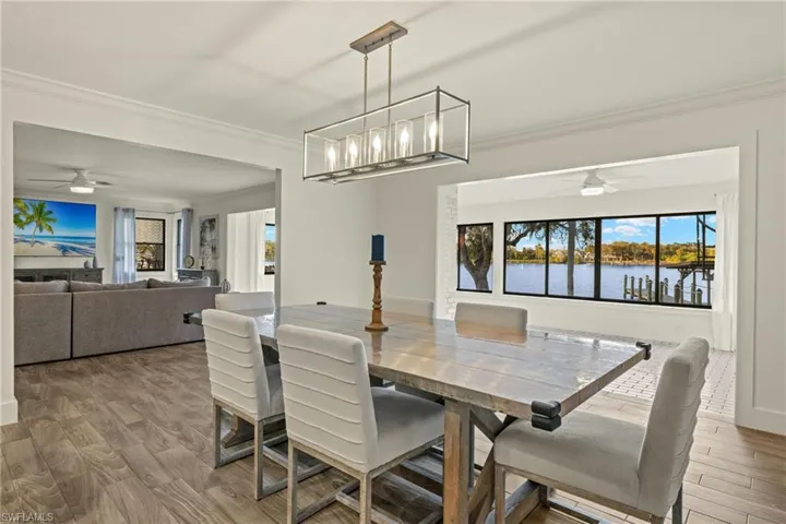 Dining room featuring hardwood / wood-style flooring, a wealth of natural light, ornamental molding, and a water view