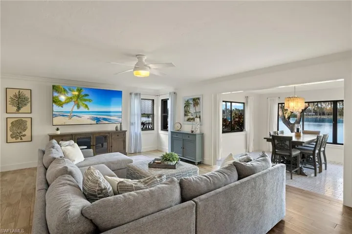 Living room featuring ornamental molding, ceiling fan with notable chandelier, and light wood-type flooring