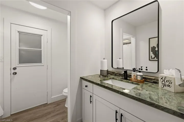 Bathroom with hardwood / wood-style flooring, vanity, and toilet