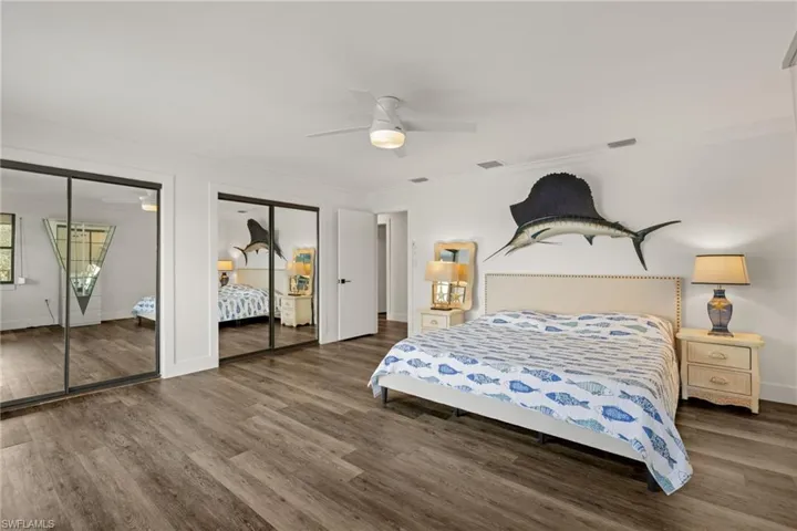 Bedroom with crown molding, ceiling fan, wood-type flooring, and two closets