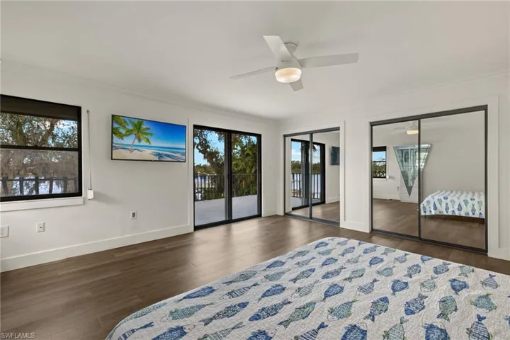 Bedroom with crown molding, ceiling fan, access to exterior, dark hardwood / wood-style flooring, and multiple closets