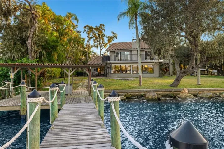 Dock area featuring a water view, a balcony, and a yard