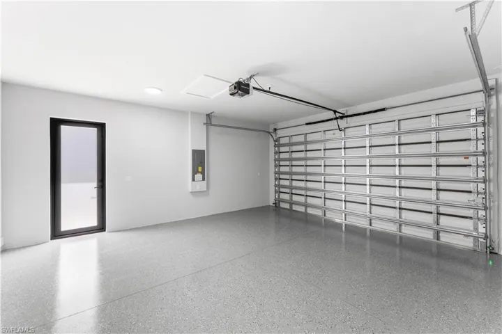 Spacious garage featuring a durable epoxy-coated floor, a large overhead garage door, and a separate full-lite exterior door