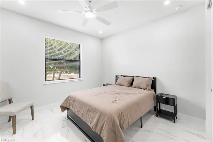 Bright interior space featuring a window with horizontal blinds, overhead ceiling fan with lighting, recessed lighting, and white tile flooring