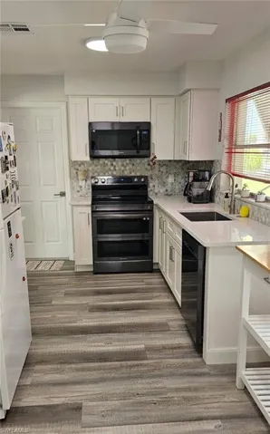 Kitchen featuring double oven range, visible vents, a sink, black dishwasher, and white cabinetry