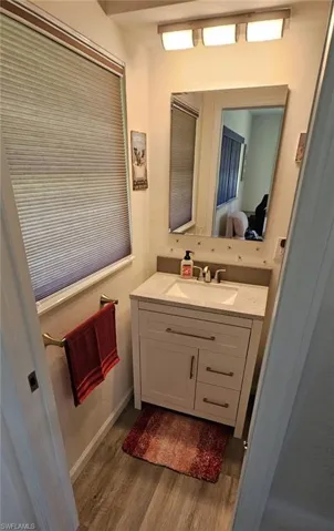 Ensuite bathroom with vanity, ensuite bath, and wood finished floors