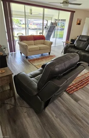 Living room featuring a ceiling fan, wood finished floors, and a healthy amount of sunlight