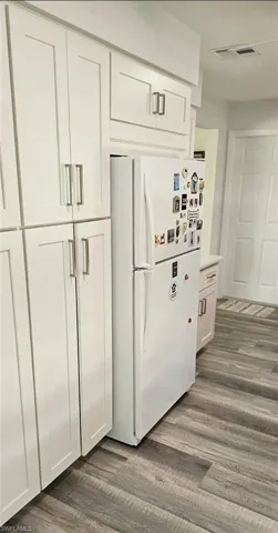 Kitchen featuring visible vents, freestanding refrigerator, white cabinets, and dark wood-type flooring