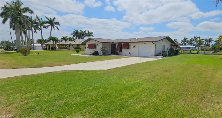Ranch-style home featuring an attached garage, concrete driveway, stucco siding, and a front yard